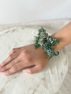 a woman's hand wearing a bracelet with pine cones and berries on it,