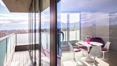 a balcony with table and chairs overlooking the city