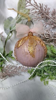 a pink ornament sitting on top of a table next to green leaves and beads