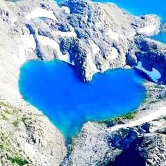 a heart shaped lake surrounded by mountains and snow in the background is an advert