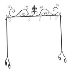 a wrought iron shelf with two hanging hooks and an ornate design on the top, against a white background