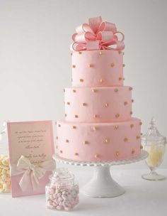 a pink wedding cake with gold polka dots on it and a card next to it