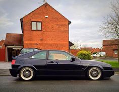 a black car parked in front of a red brick house