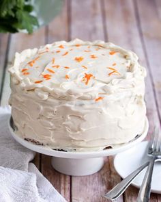 a carrot cake with frosting and orange sprinkles on a white plate