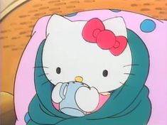 a hello kitty sitting on top of a bed with a blanket over it's head