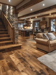 a living room filled with furniture next to a stone wall and wooden stairs in front of a kitchen