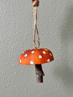 a red mushroom hanging from a rope with white dots on it's top and bottom