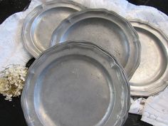 three metal plates sitting next to each other on a white lace doily with flowers in the background