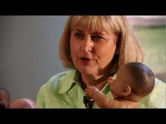 a woman holding a baby doll in her lap and looking at the camera with an angry look on her face