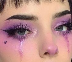 a close up of a woman with purple makeup and hearts on her cheek, looking at the camera