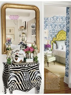 a zebra print dresser and mirror in a room with blue wallpaper, gold framed mirror, and white walls