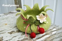 a green planter with red and white pom - poms sits on a wooden surface