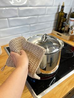 a person is cleaning the stove with a cloth and oven mitt on top of it