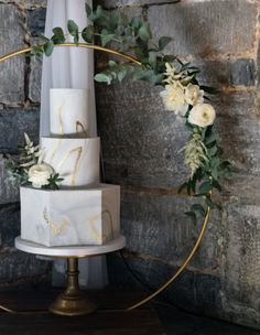 a three tiered cake with white flowers and greenery