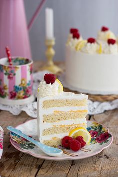 a slice of cake on a plate with raspberries and lemons next to it