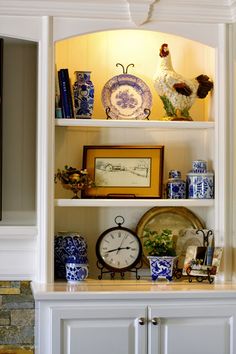 an old china cabinet with blue and white vases on it's shelves next to a clock