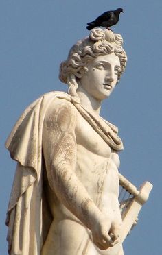 a bird sitting on top of a statue with a harp in its hand and a blue sky behind it