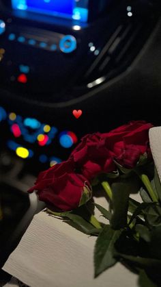 a red rose sitting on top of a table in front of a car dash board