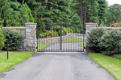 a gated driveway leading into a lush green park