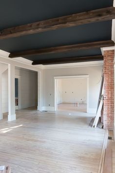 an empty living room with white walls and wood beams on the ceiling is being painted