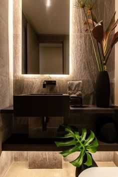 a bathroom with a sink, mirror and plant in it