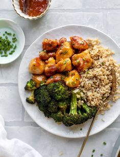 a white plate topped with chicken and broccoli covered in sauce next to rice