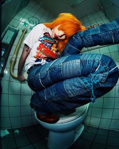 a woman with red hair sitting on top of a toilet