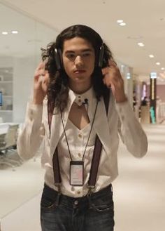 a man with long hair wearing headphones in an office building while listening to music