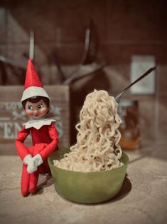 an elf is eating noodles from a green bowl