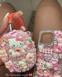 a person holding a cell phone case with hello kitty on it and other items attached to it