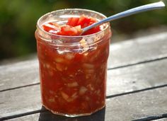 a jar filled with food sitting on top of a wooden table next to a spoon