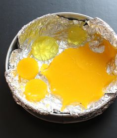 a metal bowl filled with eggs on top of a black table next to a knife and fork