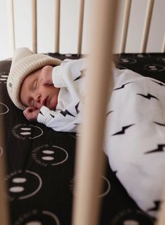 a baby sleeping in a crib wearing a hat