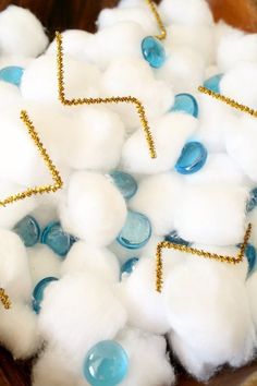 cotton balls are arranged in a bowl with gold trimmings and blue glass beads