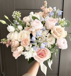 a person holding a bouquet of flowers in their hand with the door behind them open