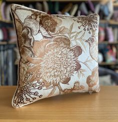 a brown and white pillow sitting on top of a wooden table next to a bookshelf