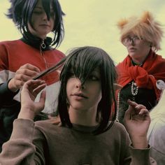 three women with short hair are sitting down and one is combing the other's hair