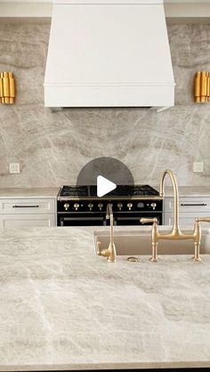 a kitchen with marble counter tops and gold faucets on the stove hoods