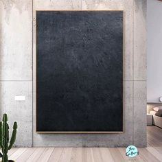 an empty room with a large blackboard on the wall next to a potted cactus