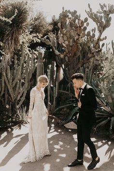 a man and woman standing next to each other in front of cacti