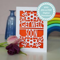 an orange and white card with the words get well soon on it next to a purple flower