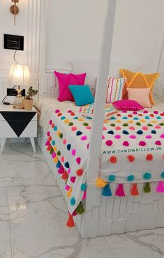 a white bed topped with lots of colorful pillows