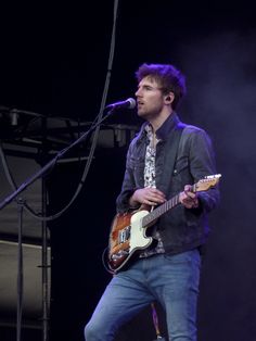 a man standing on top of a stage holding a guitar