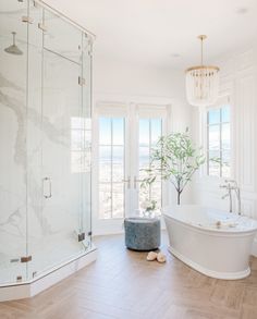 a bathroom with a large tub and walk in shower next to a window that looks out onto the ocean