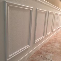 a bathroom wall with white paneling and tile flooring on the walls in front of it