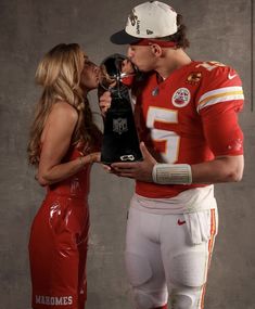 a man and woman kissing each other while wearing football uniforms