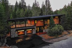 this is an aerial view of a modern house in the woods at night with lights on