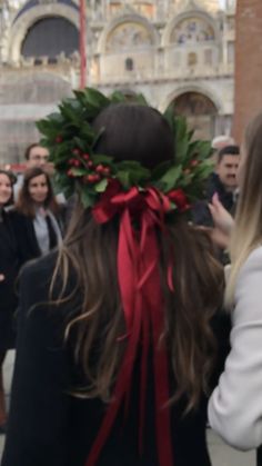 a woman with a wreath on her head is standing in front of a group of people