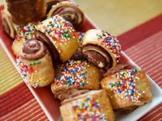 a white plate topped with lots of different types of pastries covered in sprinkles