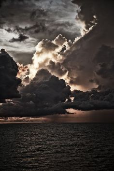 the sky is filled with dark clouds as it sits over the water in front of an ocean